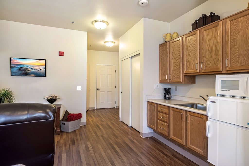A cozy apartment interior featuring a kitchen with wooden cabinets and flooring.
