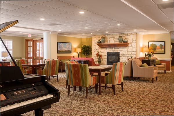 A cozy lounge area with comfortable seating and a piano near a fireplace.