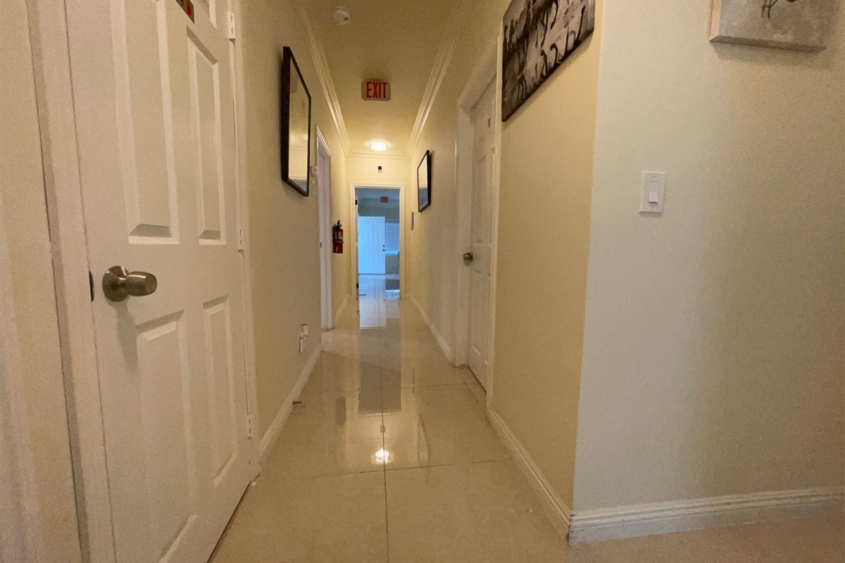 A well-lit hallway in a home featuring artwork and several doors.