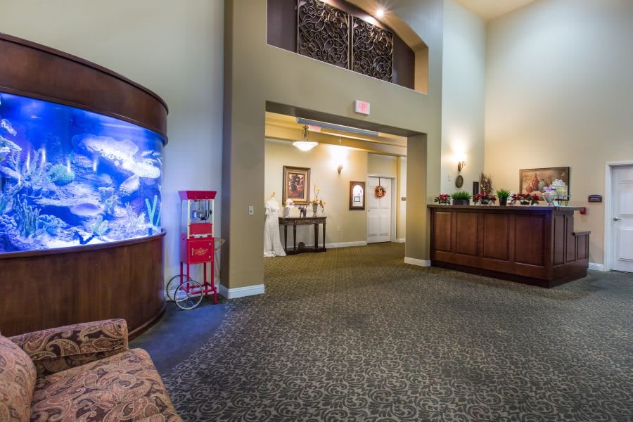 A welcoming lobby with a reception desk and a large fish tank, featuring cozy lighting and decorative elements.