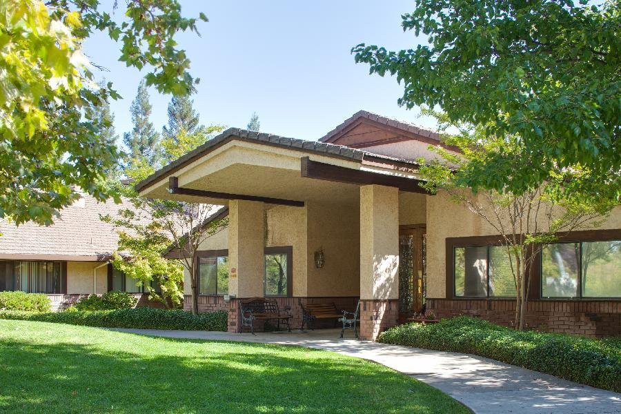 A modern residential house with a well-maintained lawn and surrounding trees.
