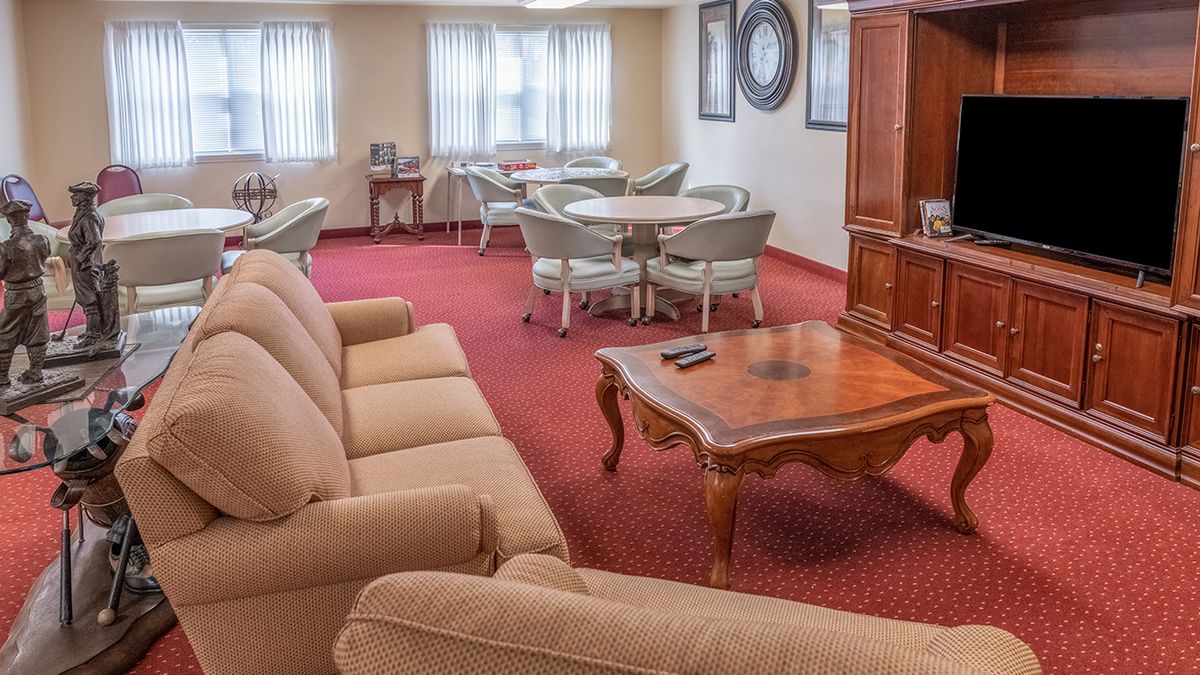 A cozy living room with a sofa, coffee table, and dining area in a well-lit space.