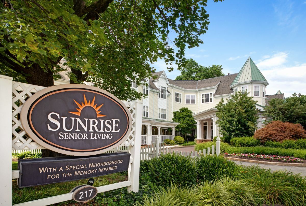 Entrance to Sunrise Senior Living with a welcoming sign and garden.