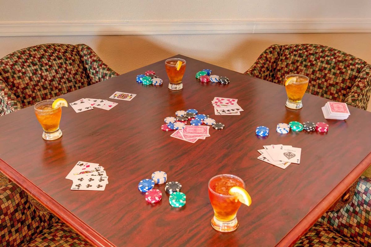 A poker game setup with cards, chips, and drinks on a table.