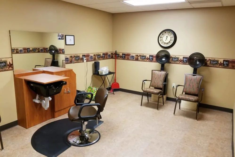 Interior of a hair salon with chairs, a mirror, and hair dryers.