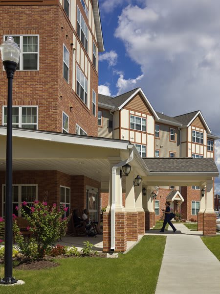 A multi-story residential building with brick exterior and covered walkways, set against a partly cloudy sky.