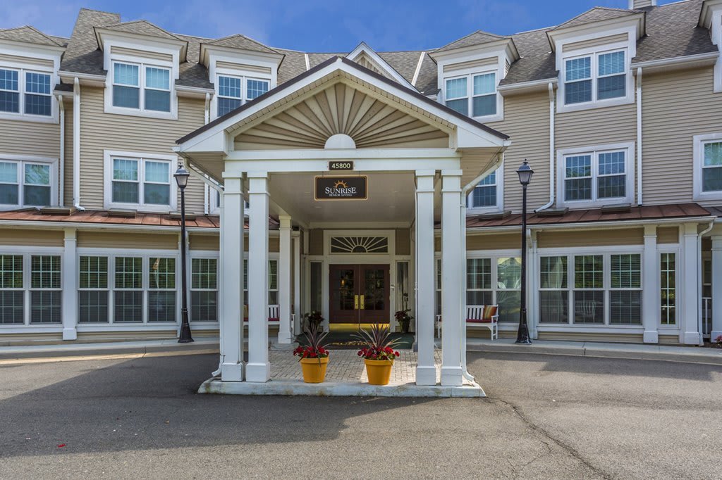 A large residential building with a prominent entrance featuring columns and a covered porch.