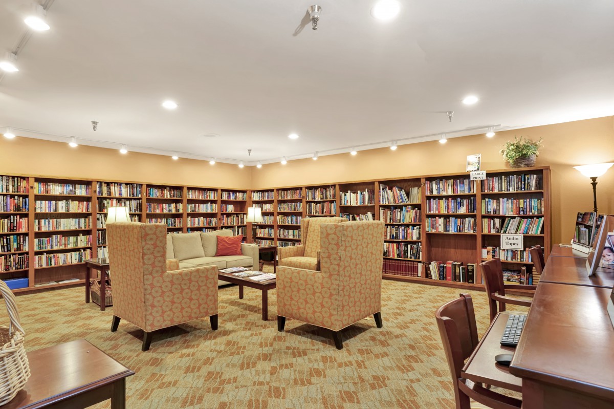 A cozy library with bookshelves lining the walls and a comfortable seating area in the center.