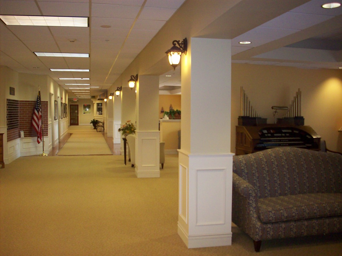 A well-lit office hallway with carpeted flooring and comfortable seating.