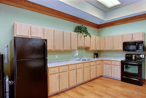 A modern kitchen featuring wooden cabinets and green walls, equipped with essential appliances.