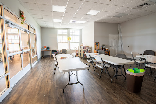 A spacious and bright room featuring several tables and chairs, suitable for meetings or classes.