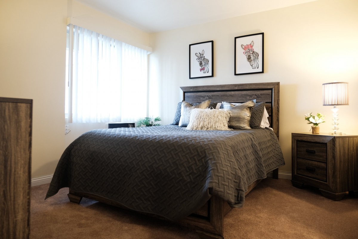 A cozy bedroom with a stylish bed and framed artwork on the wall.