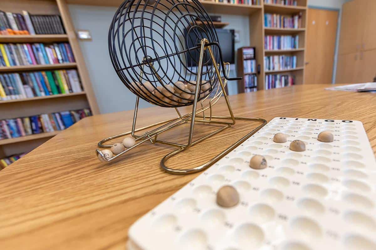 A bingo game setup with a cage and numbered balls ready for play in a library setting.