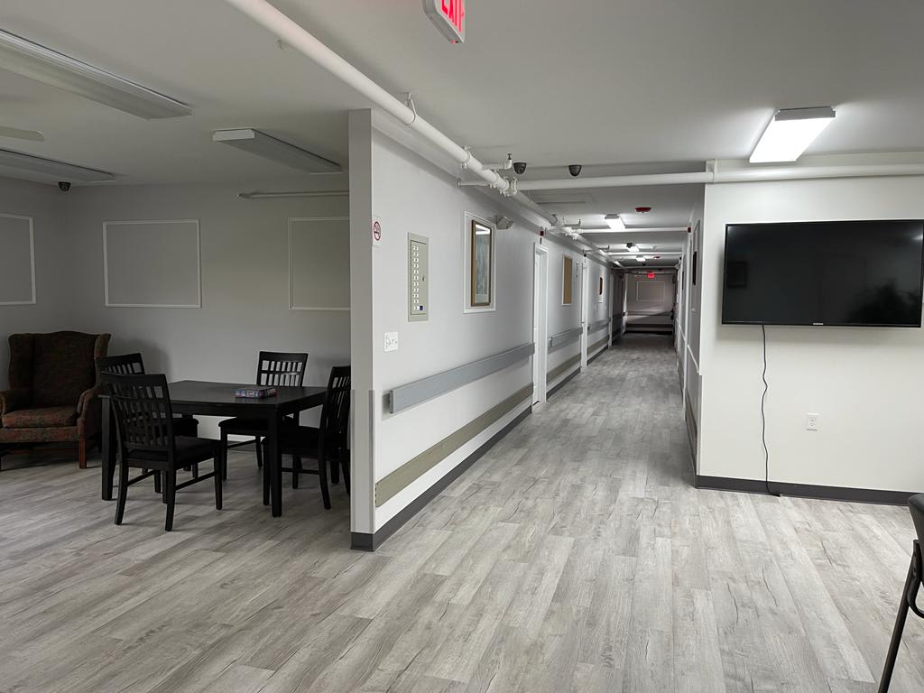 A long corridor with modern flooring and furniture in a building interior.