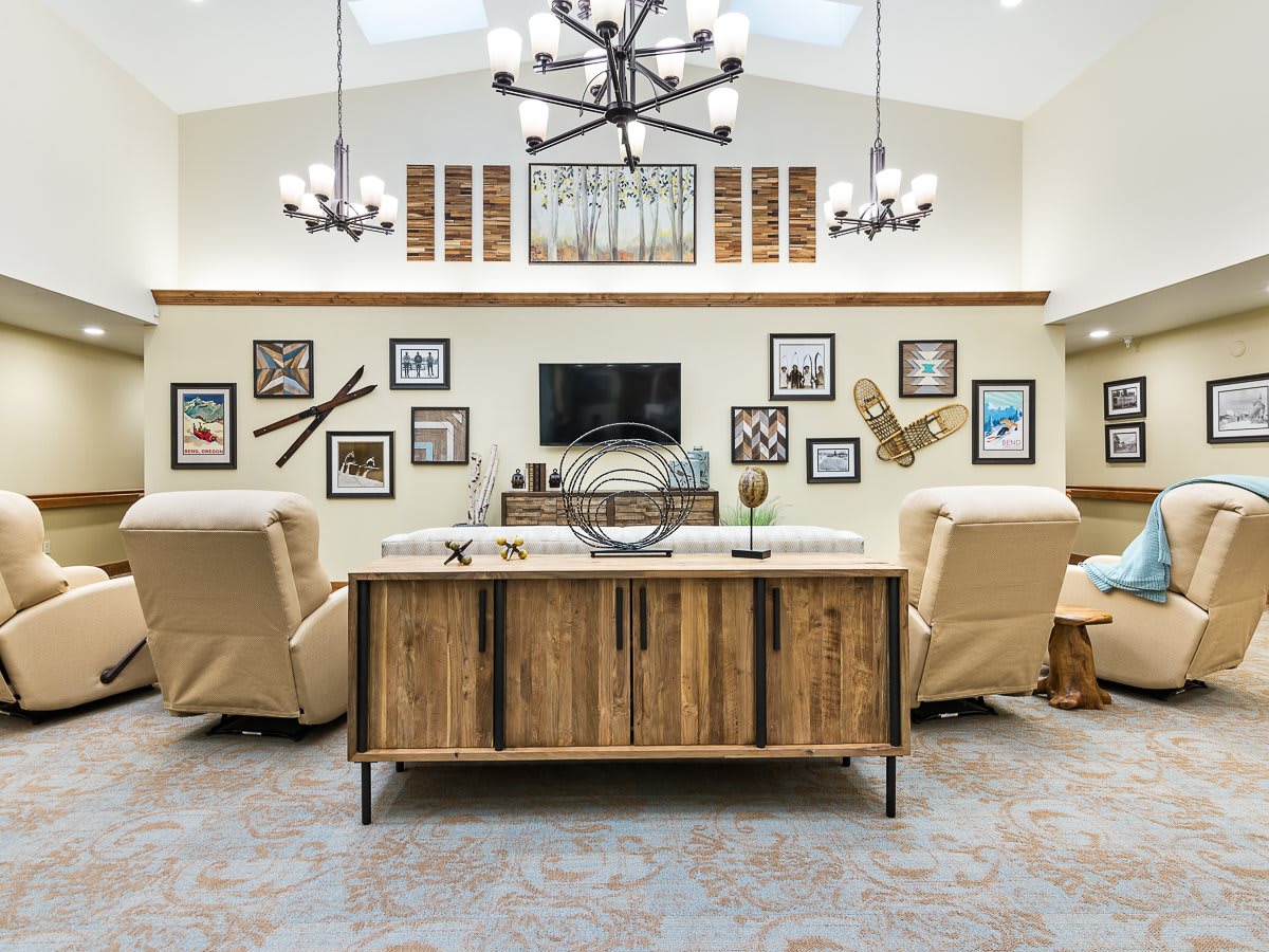 A stylish living room featuring a modern rustic design with a gallery wall, comfortable seating, and a central chandelier.