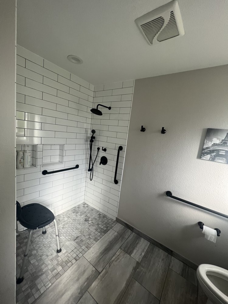 A modern, accessible bathroom with a walk-in shower, featuring grab bars and a shower seat.