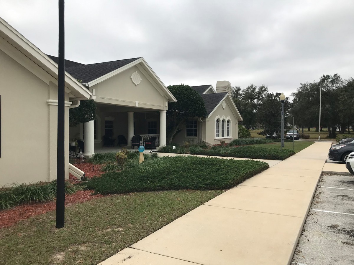 A suburban area featuring a building with a landscaped garden and a sidewalk on a cloudy day.