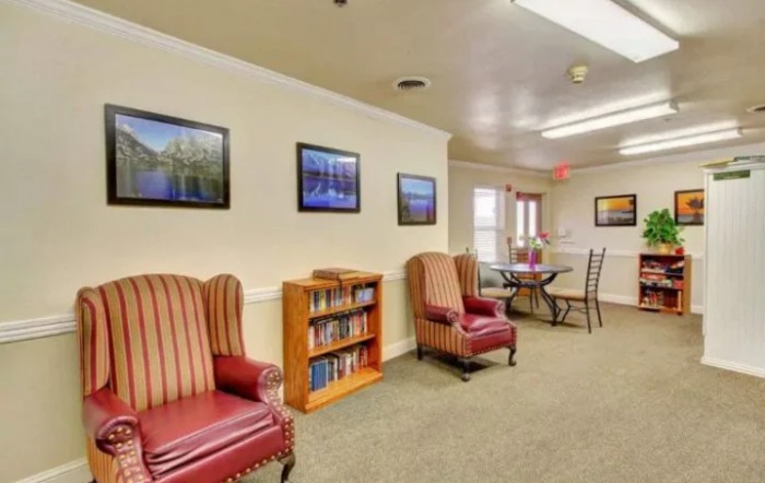 A cozy living room with comfortable chairs, a bookshelf, and wall artwork.