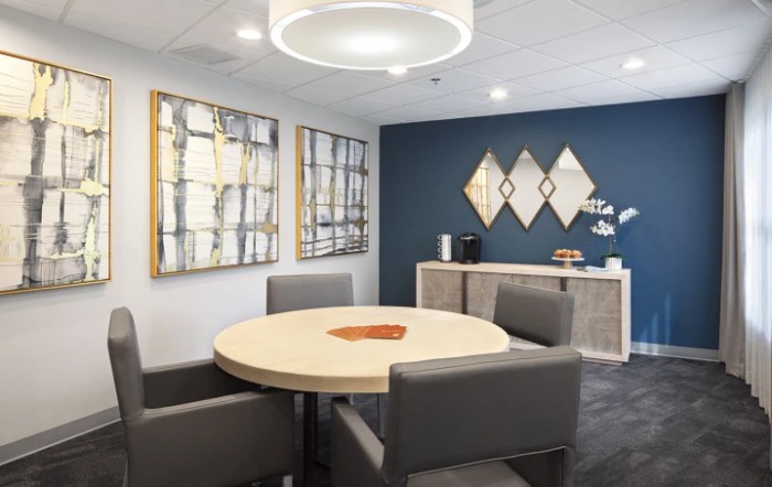 A modern office meeting room with a round table and abstract art on the walls.