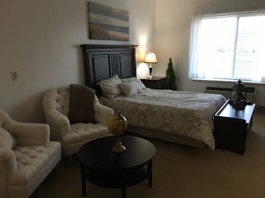 A cozy bedroom with a bed, armchairs, and a coffee table.