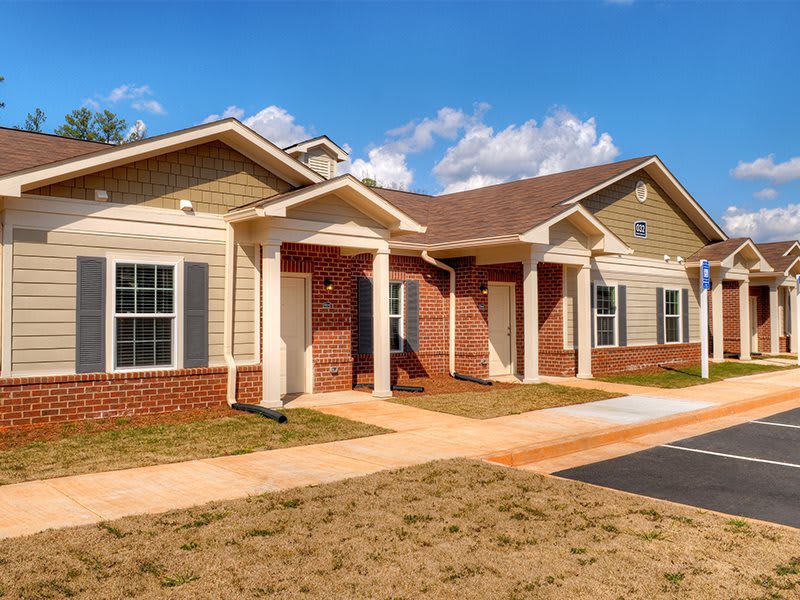 A suburban residential house with a brick facade and well-kept exterior under a clear blue sky.