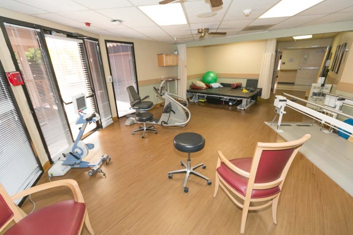 A rehabilitation facility with various exercise equipment and seating for physical therapy sessions.