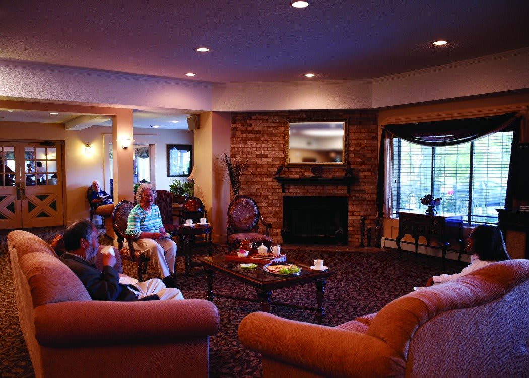 A cozy living room with a fireplace and people relaxing on couches.