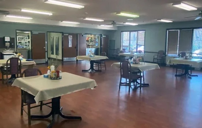 An empty dining room with arranged tables and chairs, ready for service.