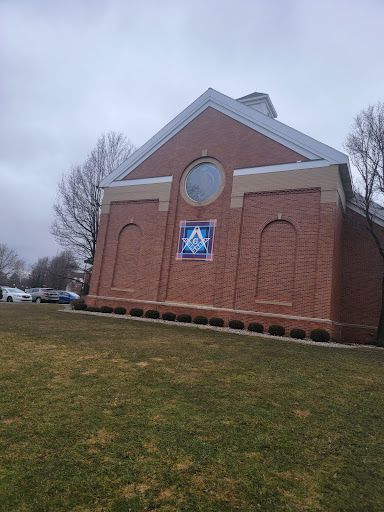 A brick building with a circular window and a banner, set against a cloudy sky.
