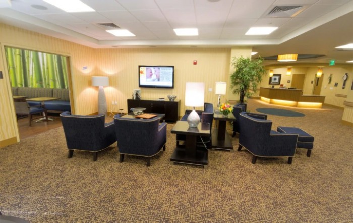 A cozy waiting room featuring comfortable chairs, a television, and ambient lighting.