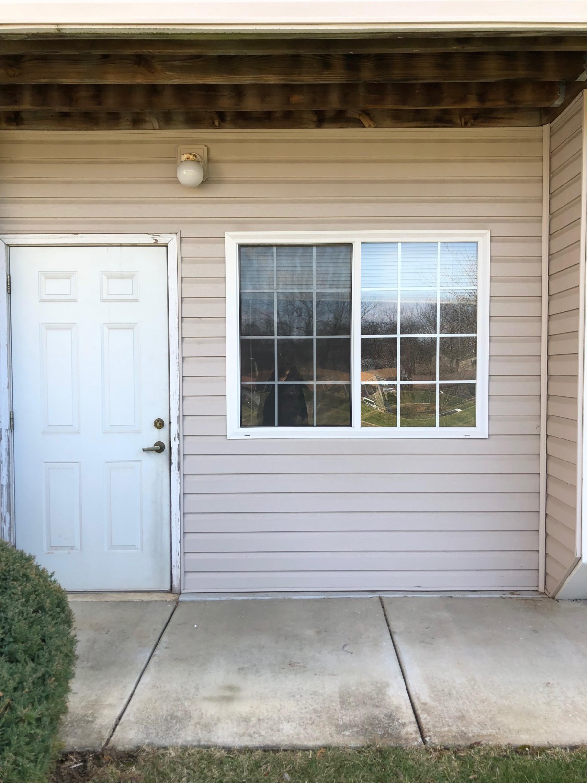 Exterior view of a house entrance with a white door and adjacent window.