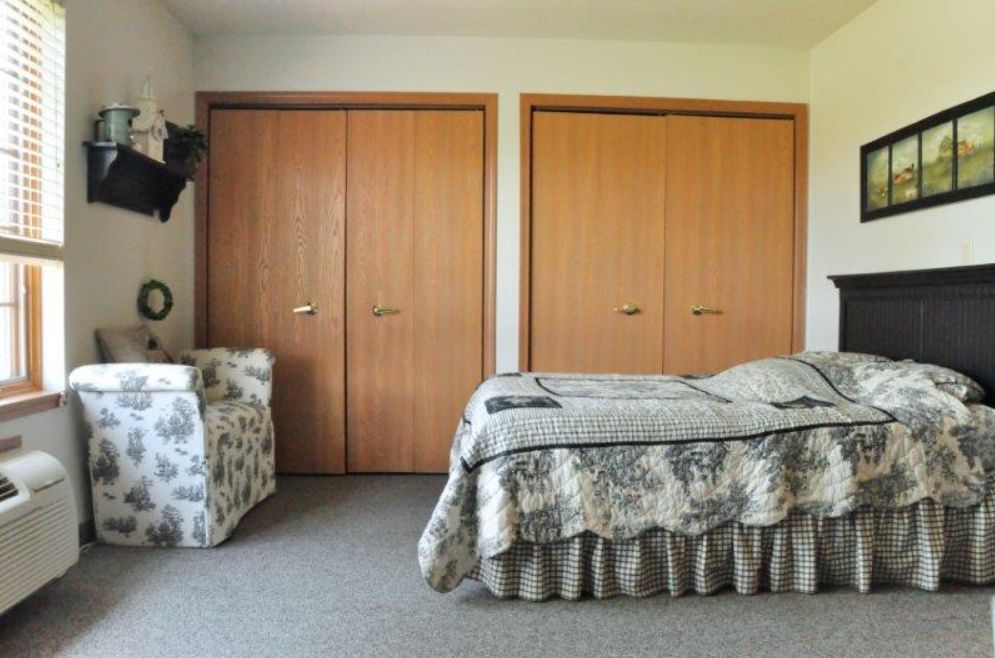 A simple bedroom with a bed, carpet, and double closets.