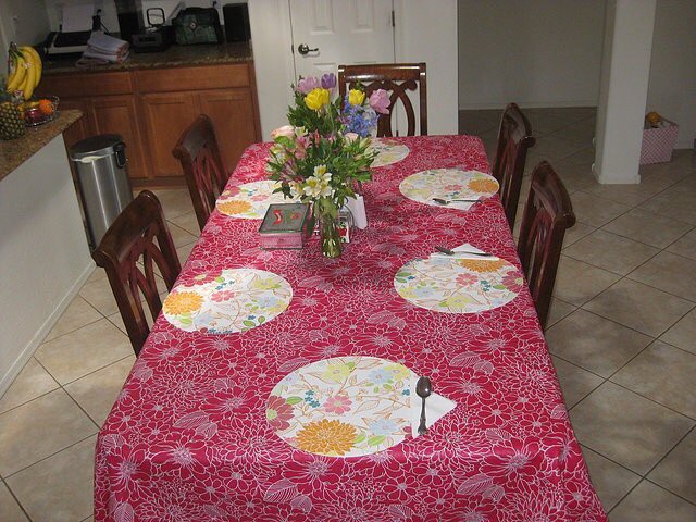 A dining table set with a colorful tablecloth and floral centerpiece.