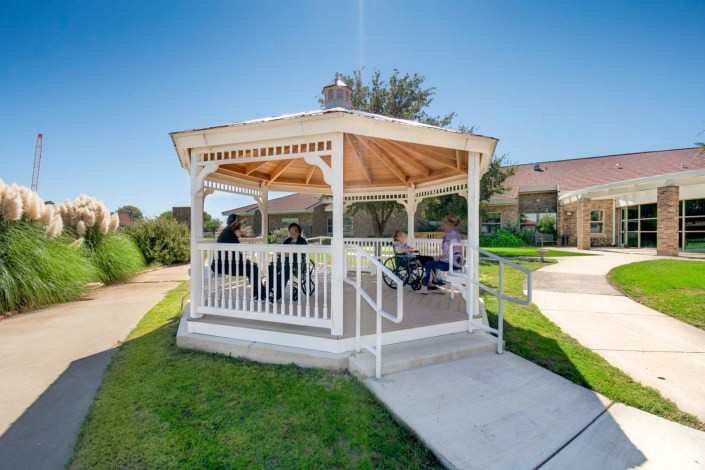 A charming white gazebo in a sunny park setting.