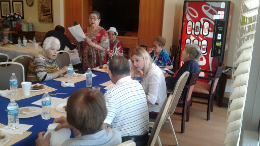 A group of individuals engaged in a meeting, participating in a discussion led by a speaker.