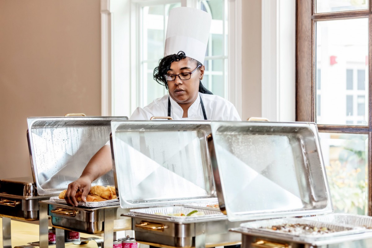 A chef preparing a buffet setup with various dishes.