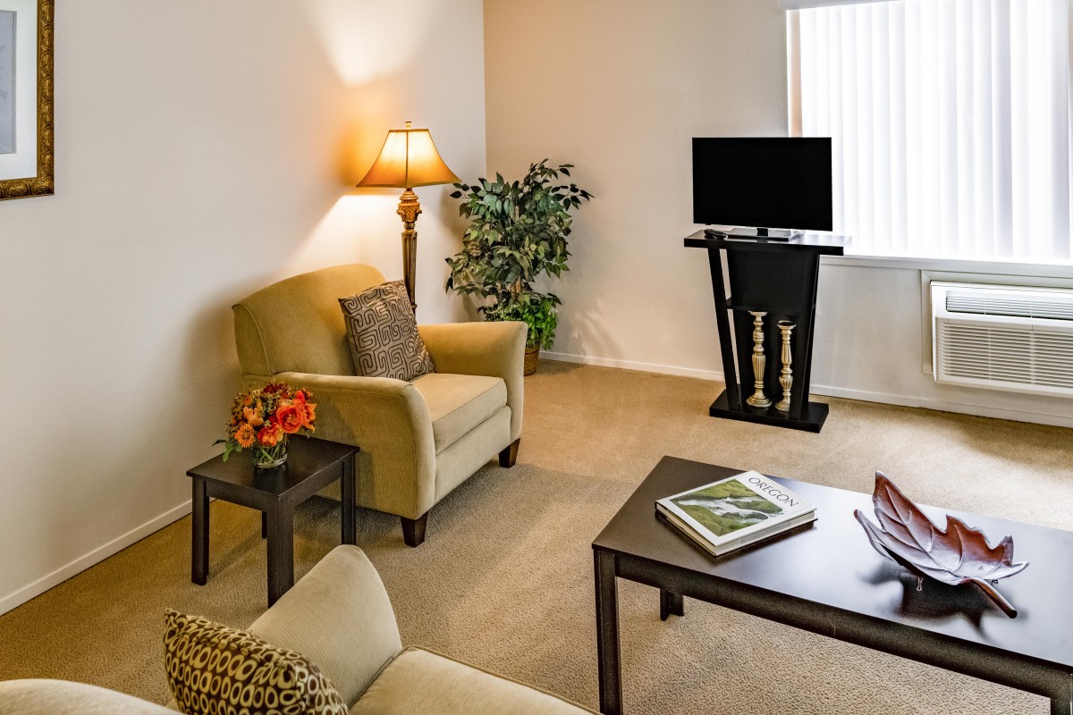 A cozy living room with armchairs, a coffee table, and a television.