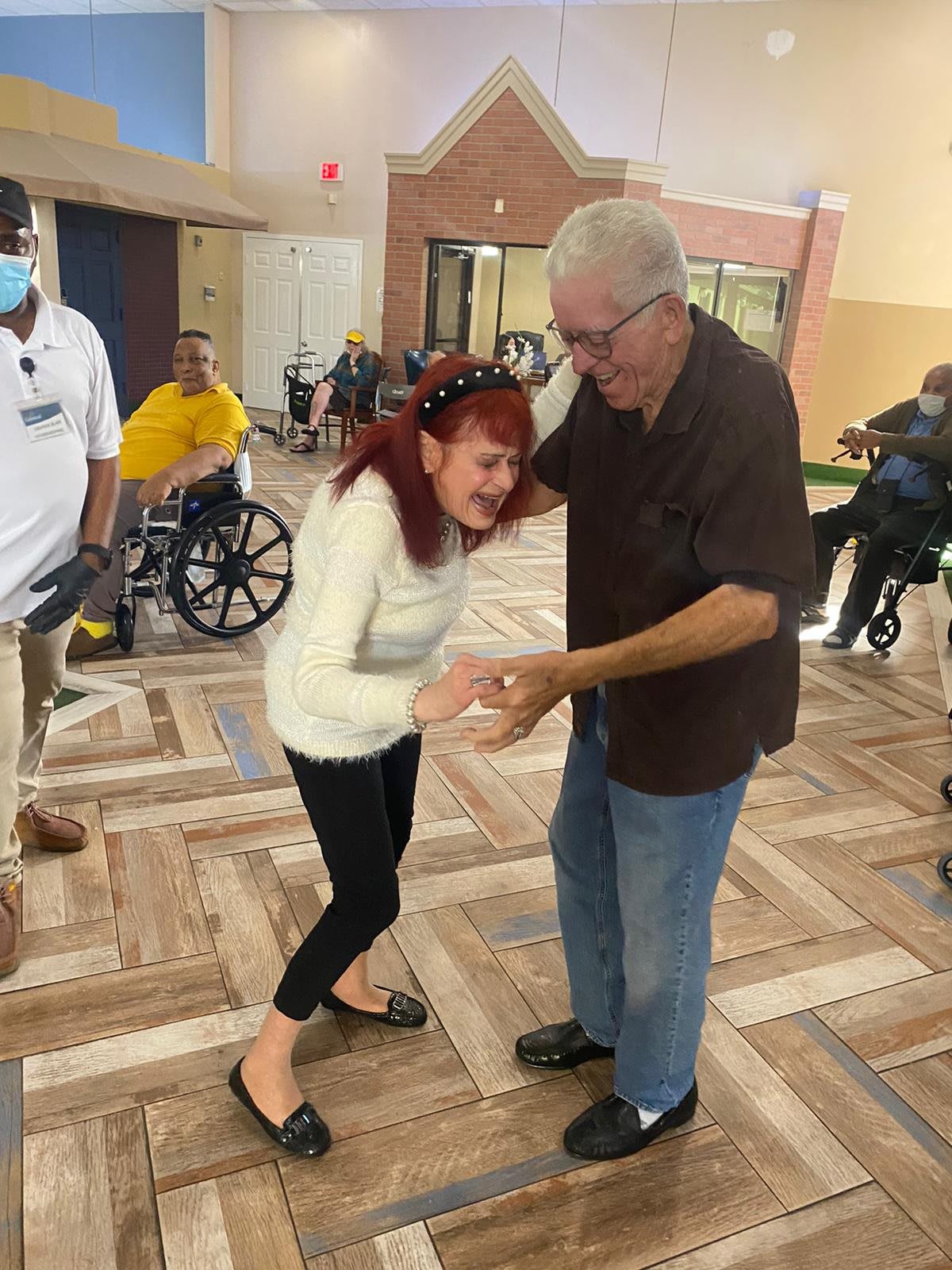 An elderly couple joyfully dancing together in a nursing home.