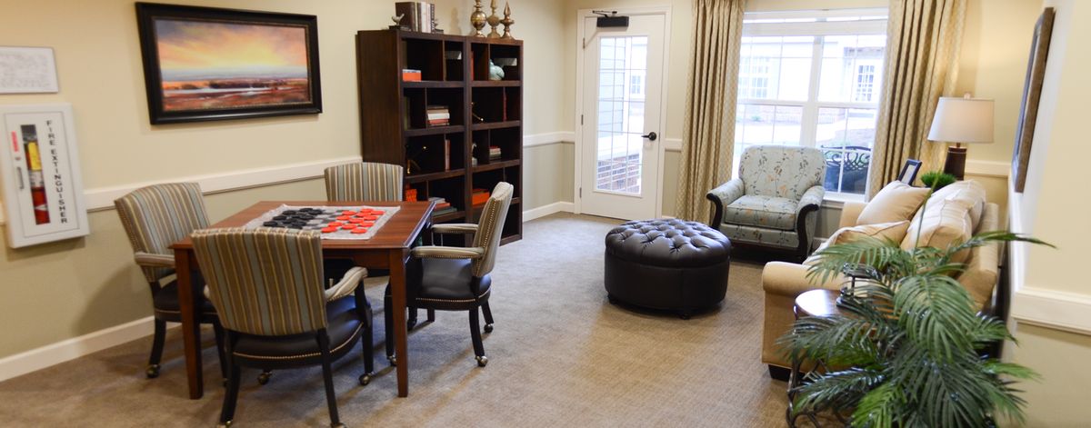A cozy living room with a table, chairs, and a bookshelf next to a window.