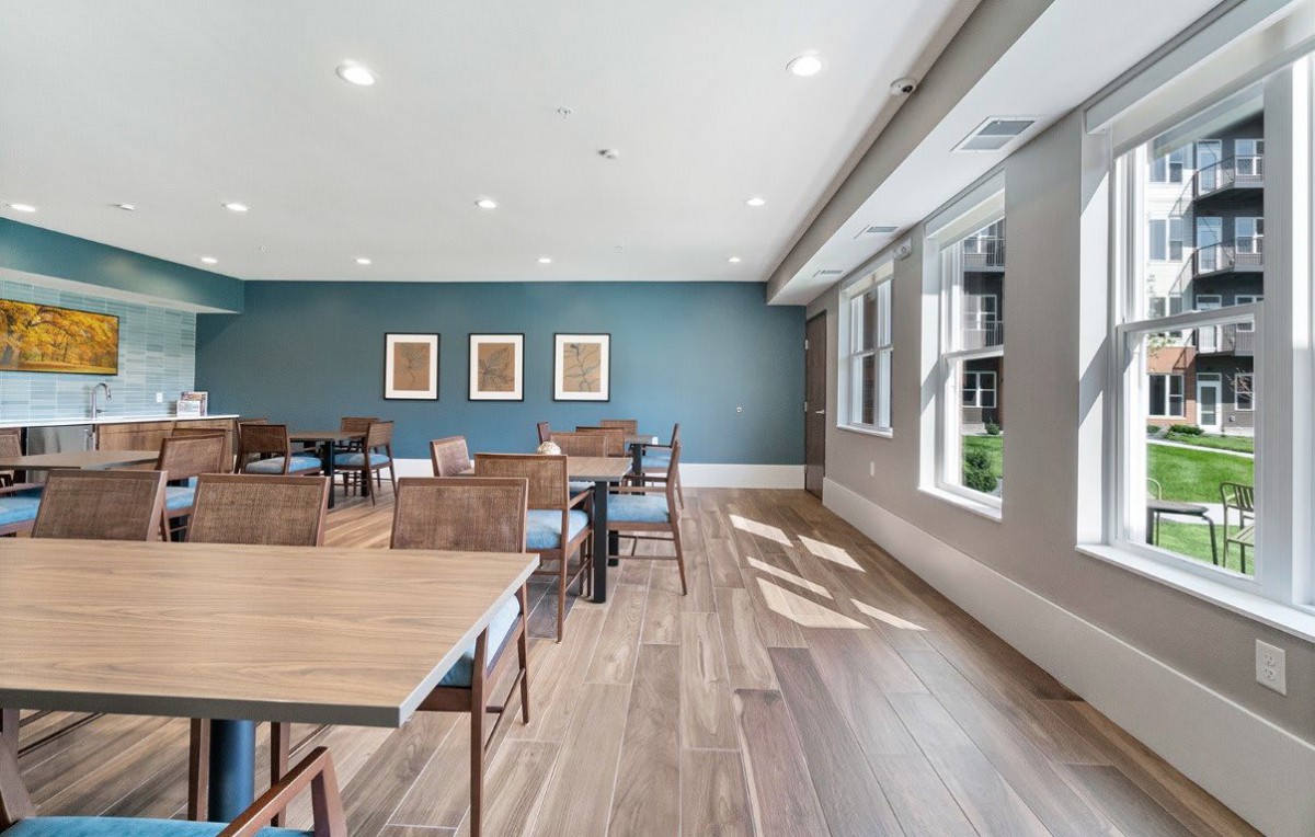 A spacious dining area with wooden floors, modern tables and chairs, and artwork on the walls.