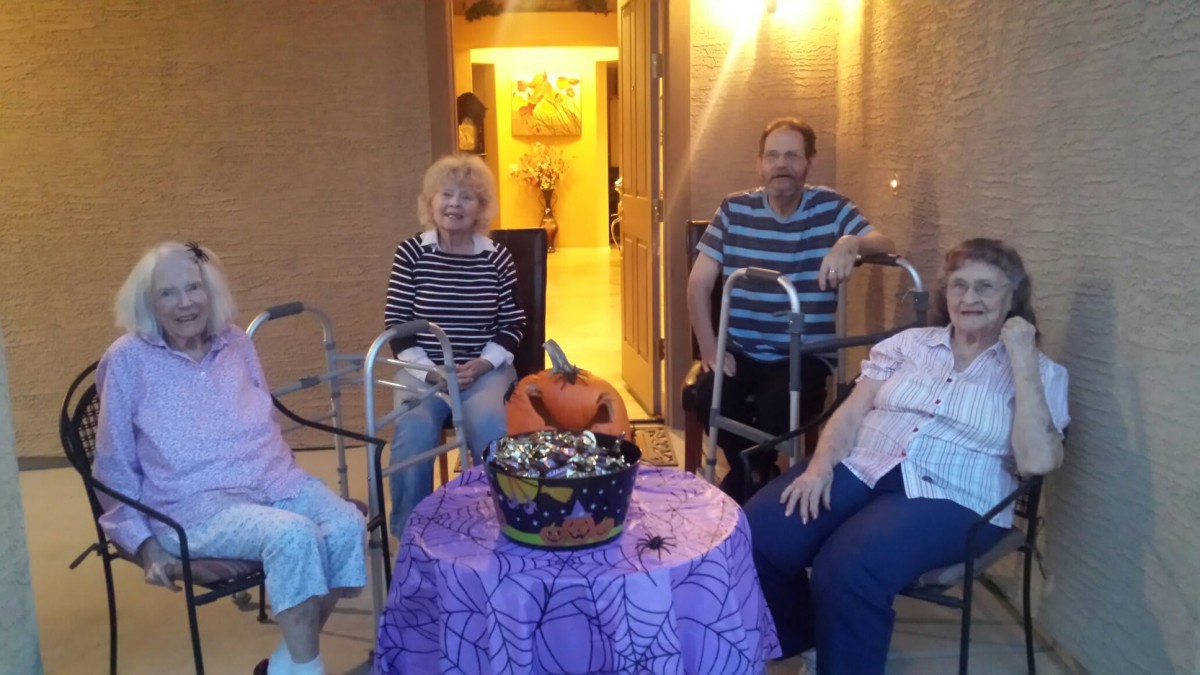 A group of seniors celebrating Halloween, gathered around a table with candy and festive decorations.