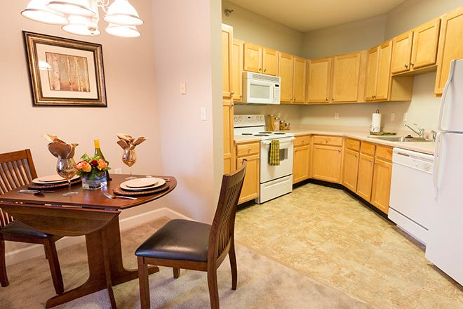 A cozy kitchen and dining area featuring wooden cabinets, a round table with chairs, and home appliances.