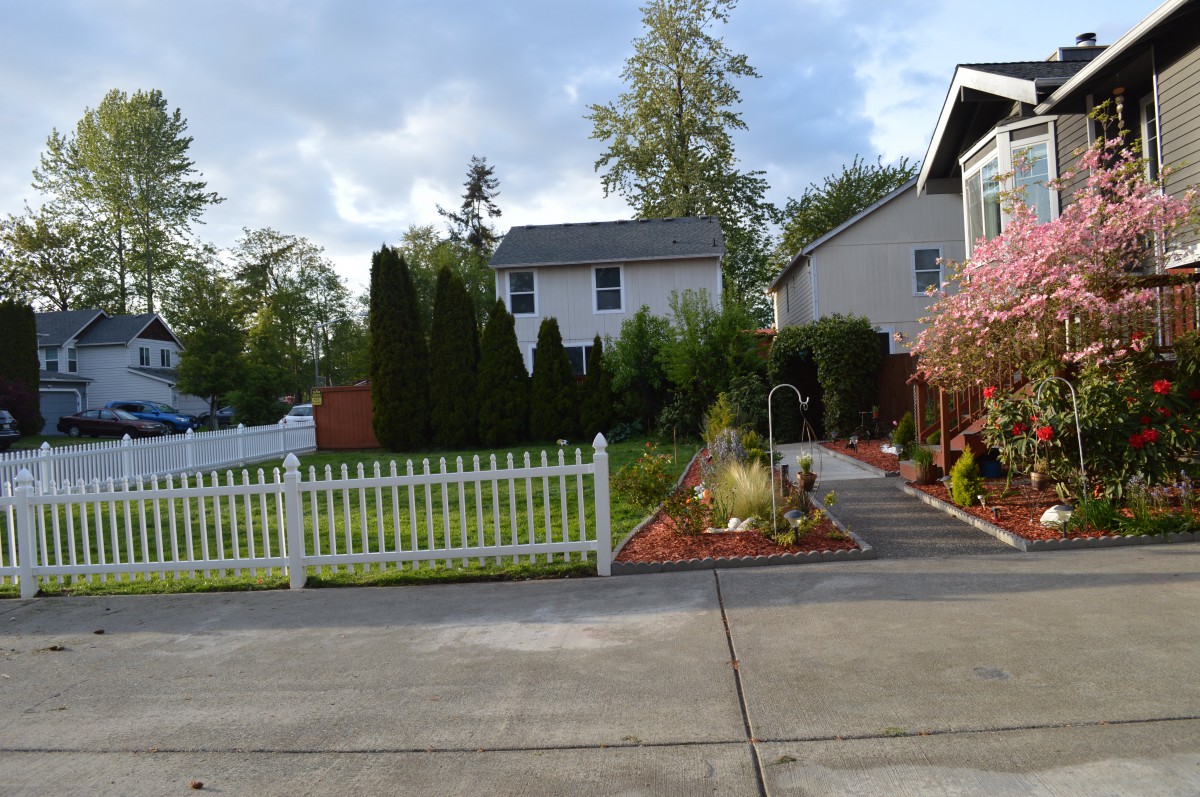 A suburban home with a neatly maintained garden and white picket fence.