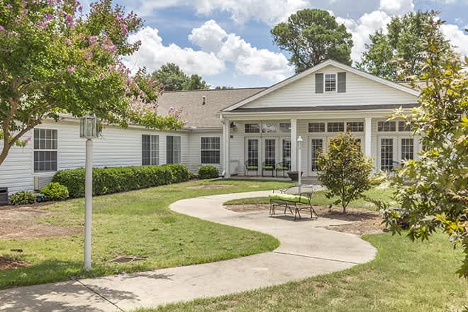 A charming single-story house with a well-maintained lawn and a curved pathway leading to the entrance.