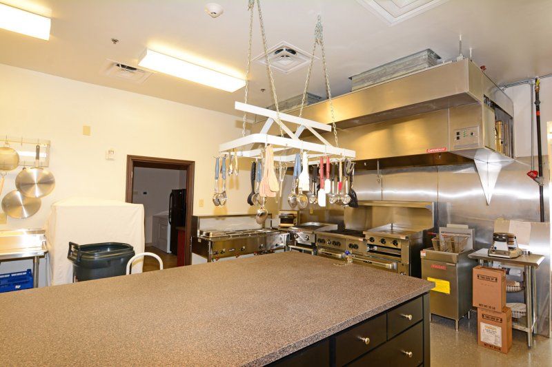 A well-equipped commercial kitchen with hanging utensils and stainless steel appliances.