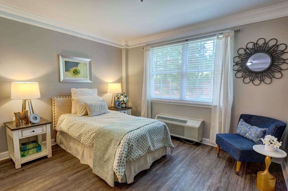 A cozy bedroom with a single bed, wooden floors, and soft lighting.