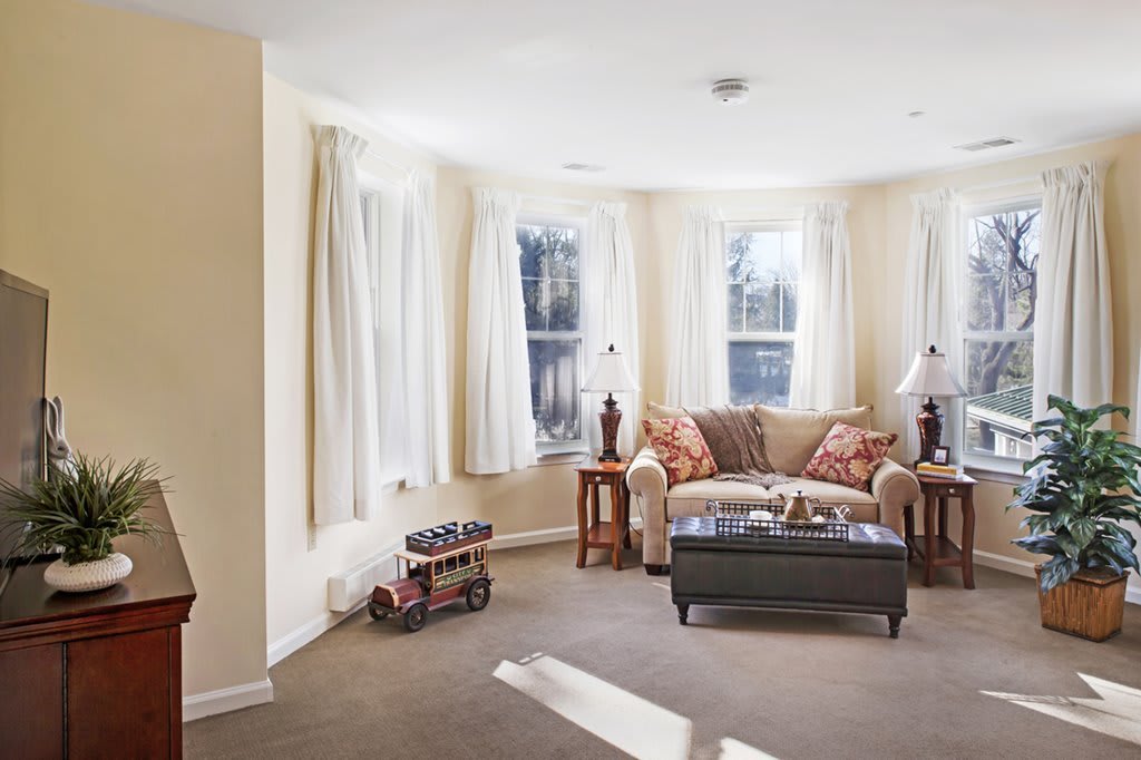A cozy living room with a sofa, coffee table, and large windows allowing natural light to fill the space.