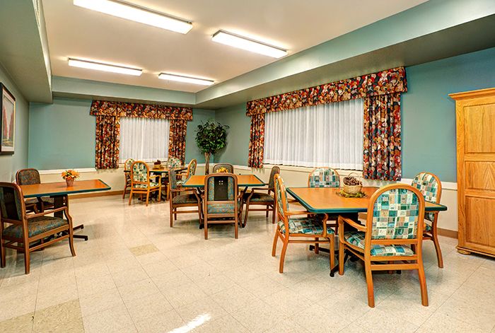 A dining room with multiple tables and chairs arranged neatly under bright lighting.