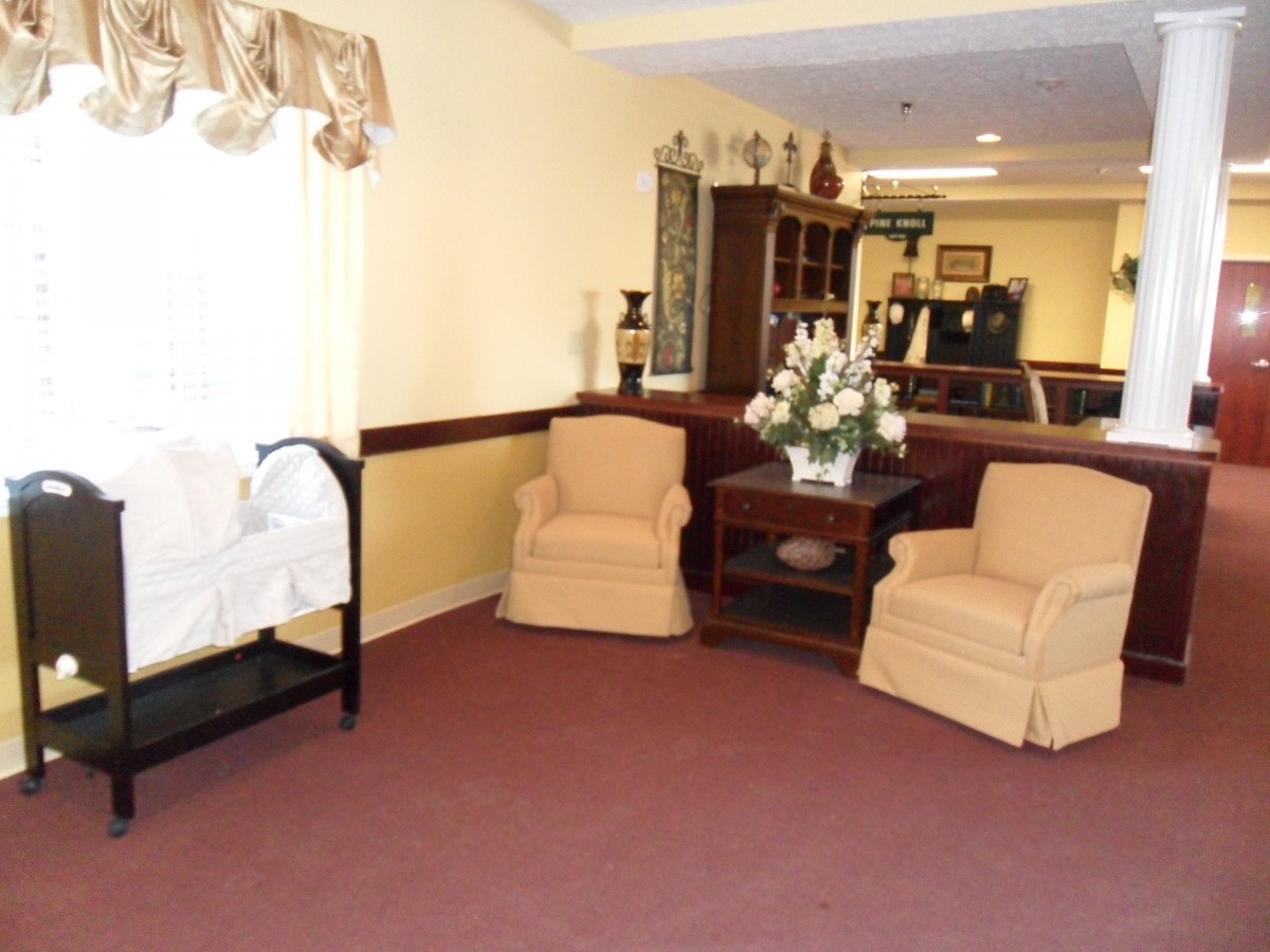 A cozy living room with armchairs, a central table adorned with a flower arrangement, and soft lighting.