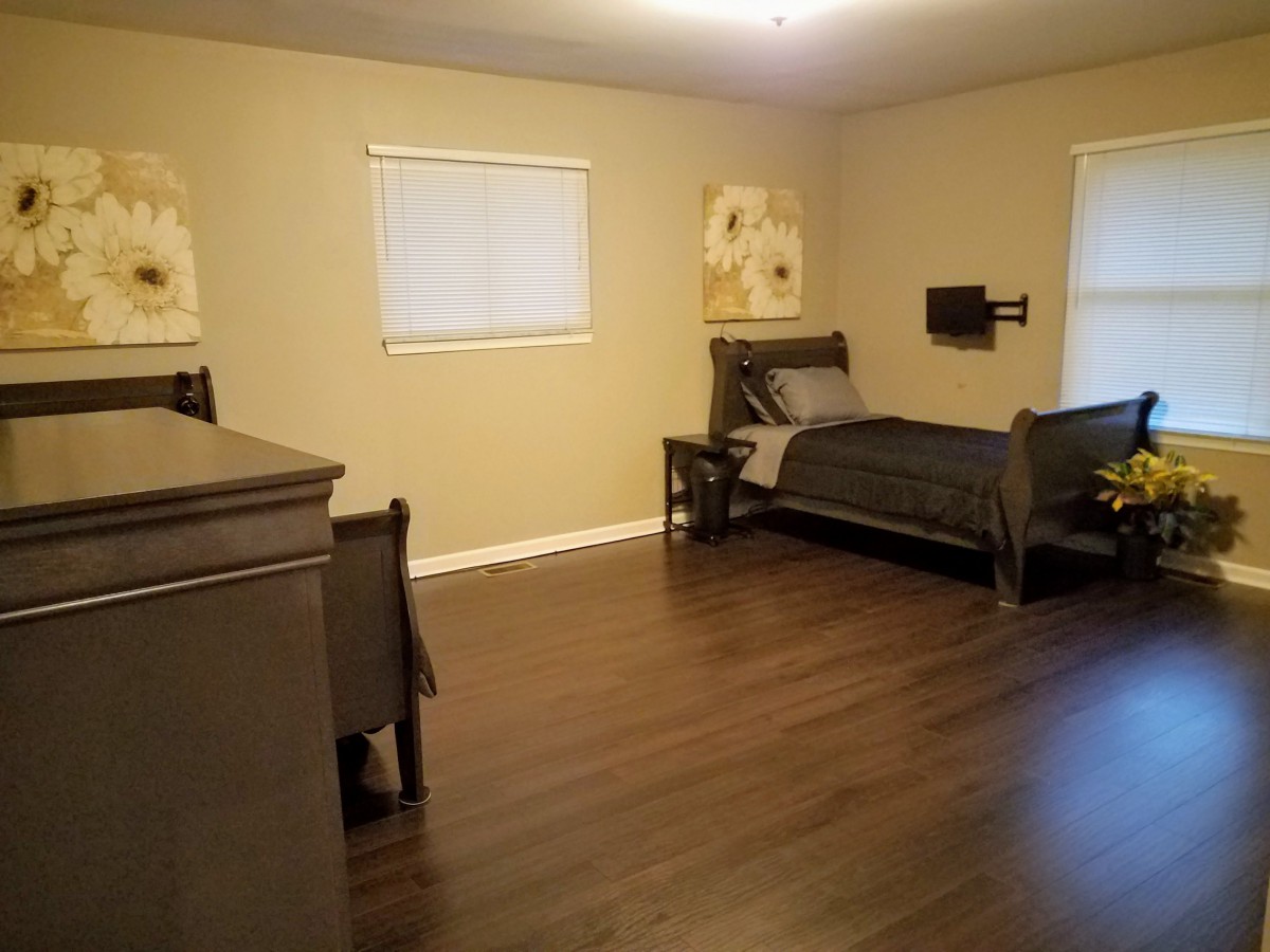 A spacious bedroom with a single bed and hardwood flooring.